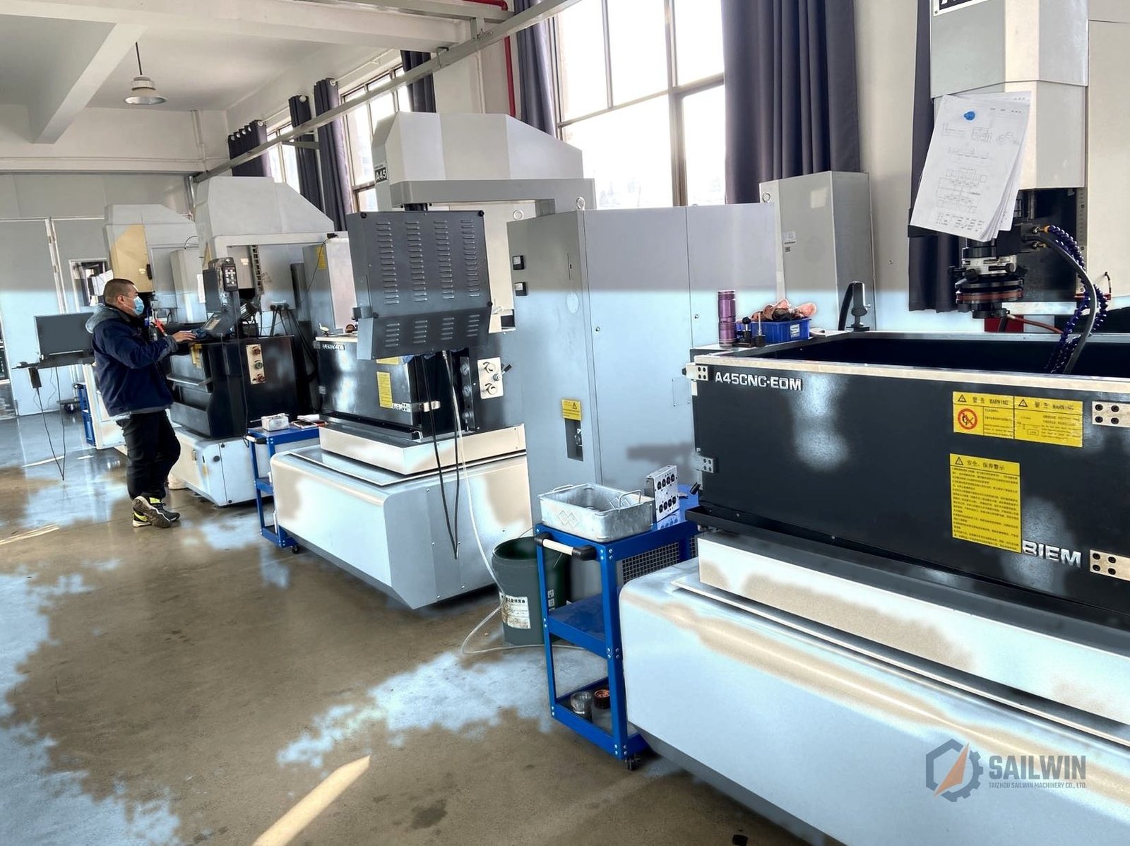 Sailwin CNC EDM die sinking machinery bay with operator and distressed blue floor Sailwin